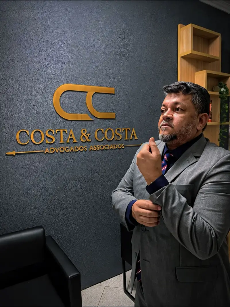 Doutor Jocinei Costa de terno cinza ao lado da logomarca do escritório